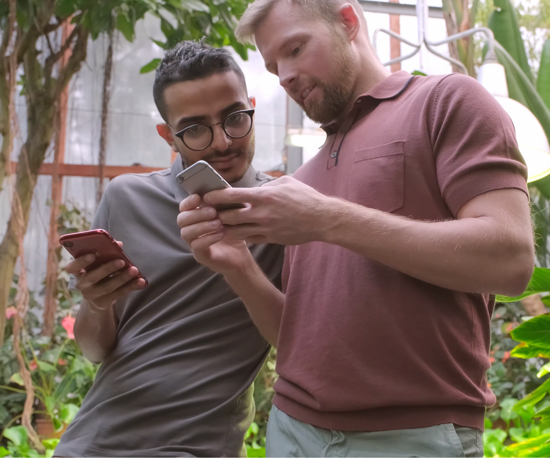 Two men looking at a phone together in a garden setting